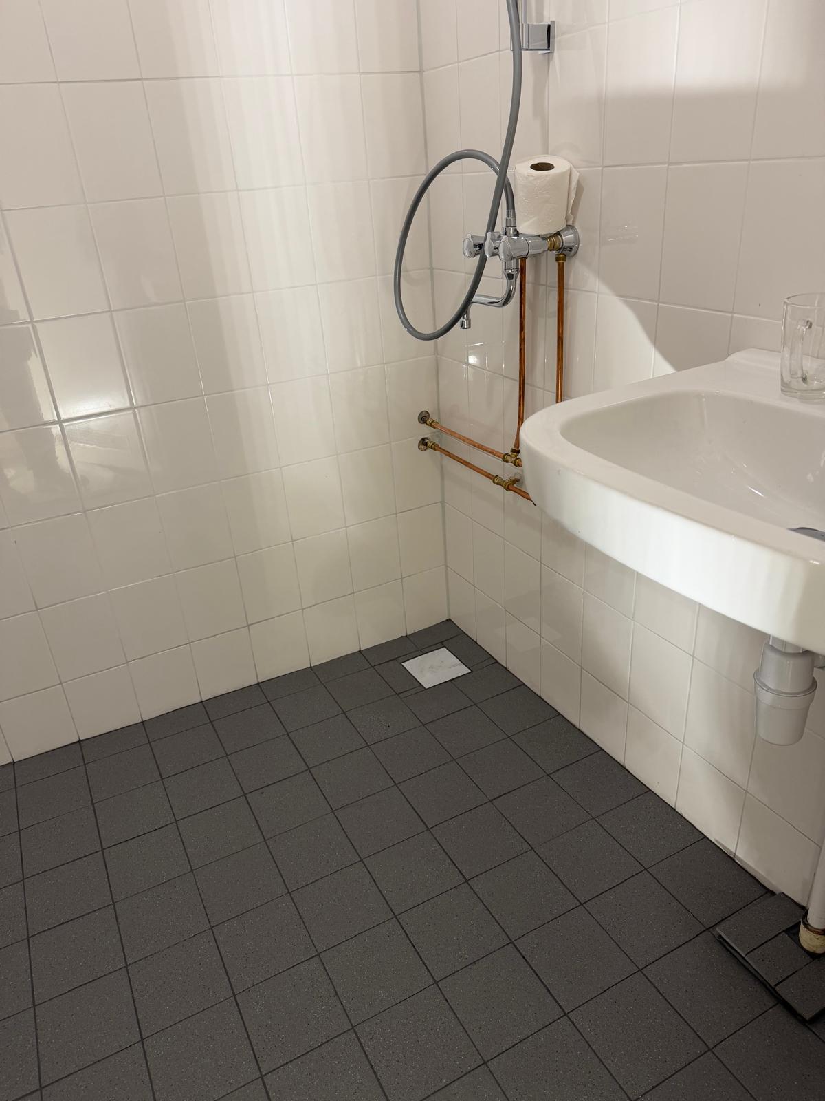 Afgewerkte badkamer met nieuw tegelwerk, douche en wastafel, tegelklus door Klussen Fixer