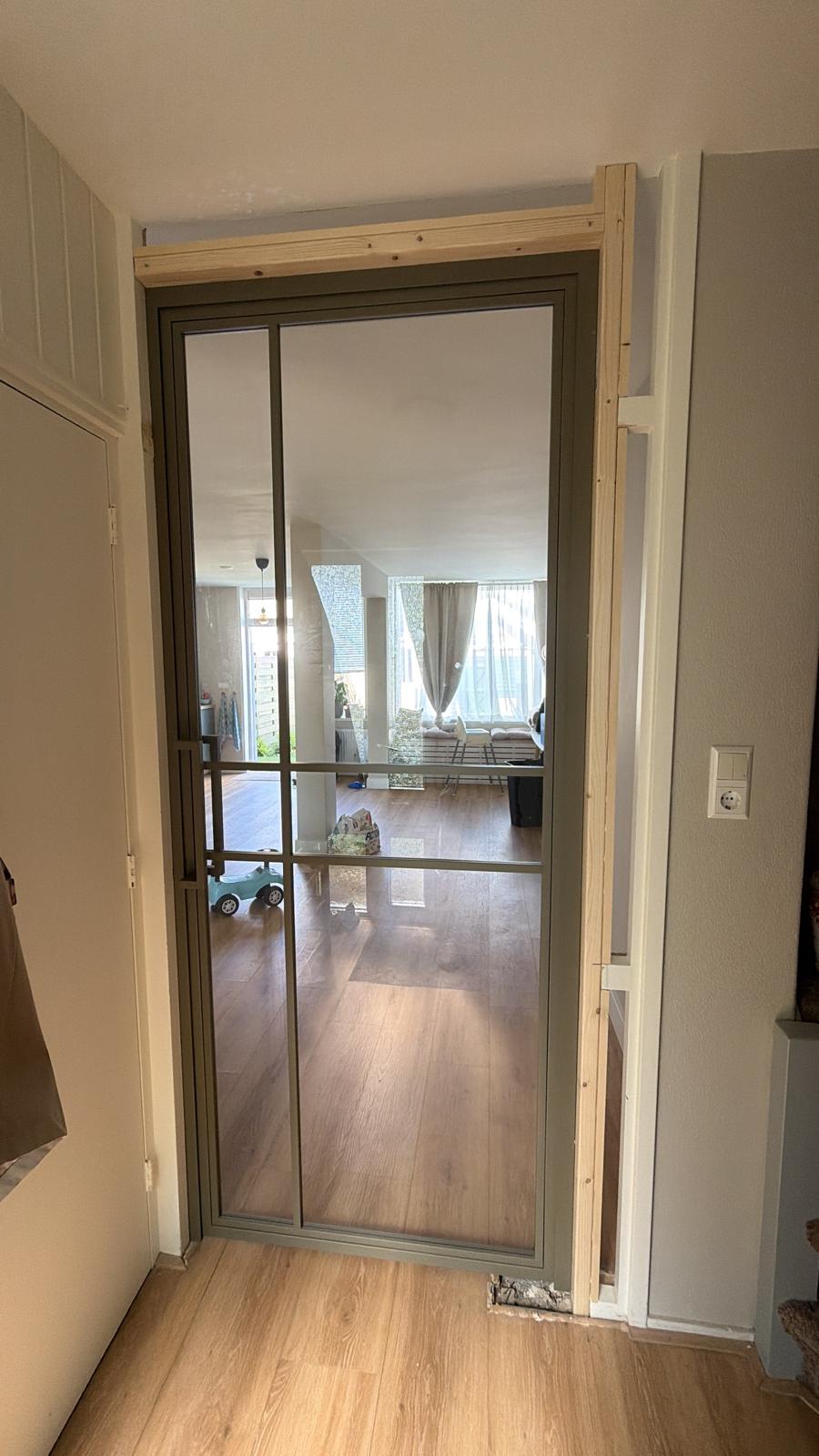 Nieuwe stalen taatsdeur met glas geplaatst tussen twee kamers door Klussen Fixer